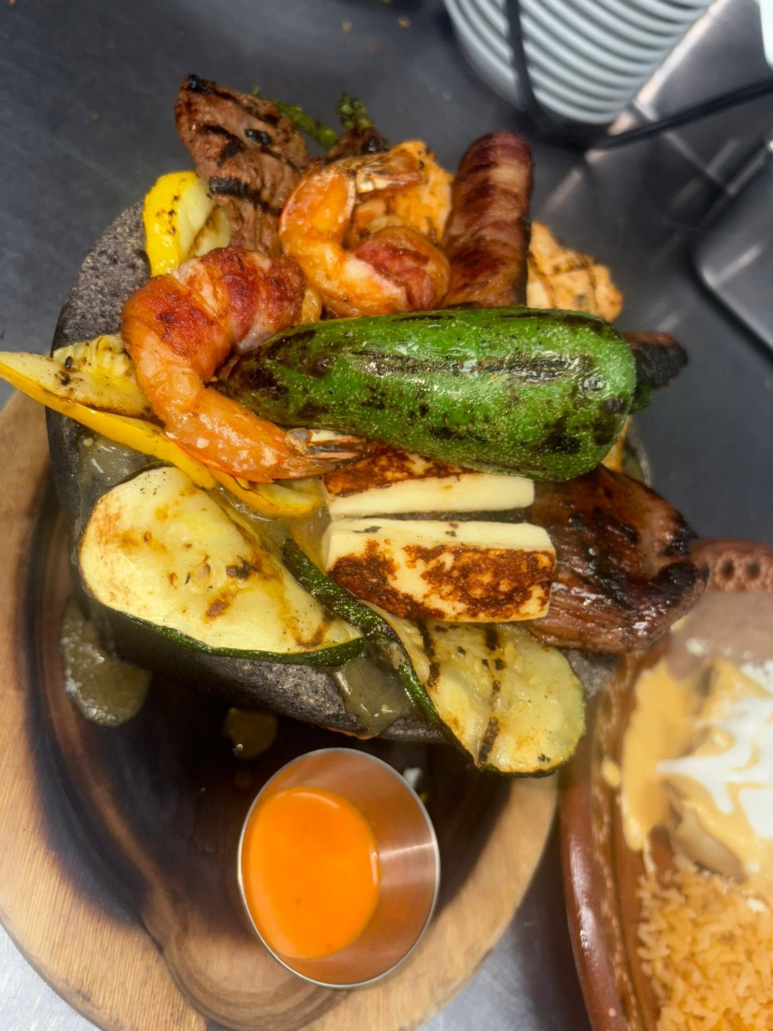 Stone platter with grilled steak, bacon-wrapped shrimp, a roasted jalapeño and grilled vegetables