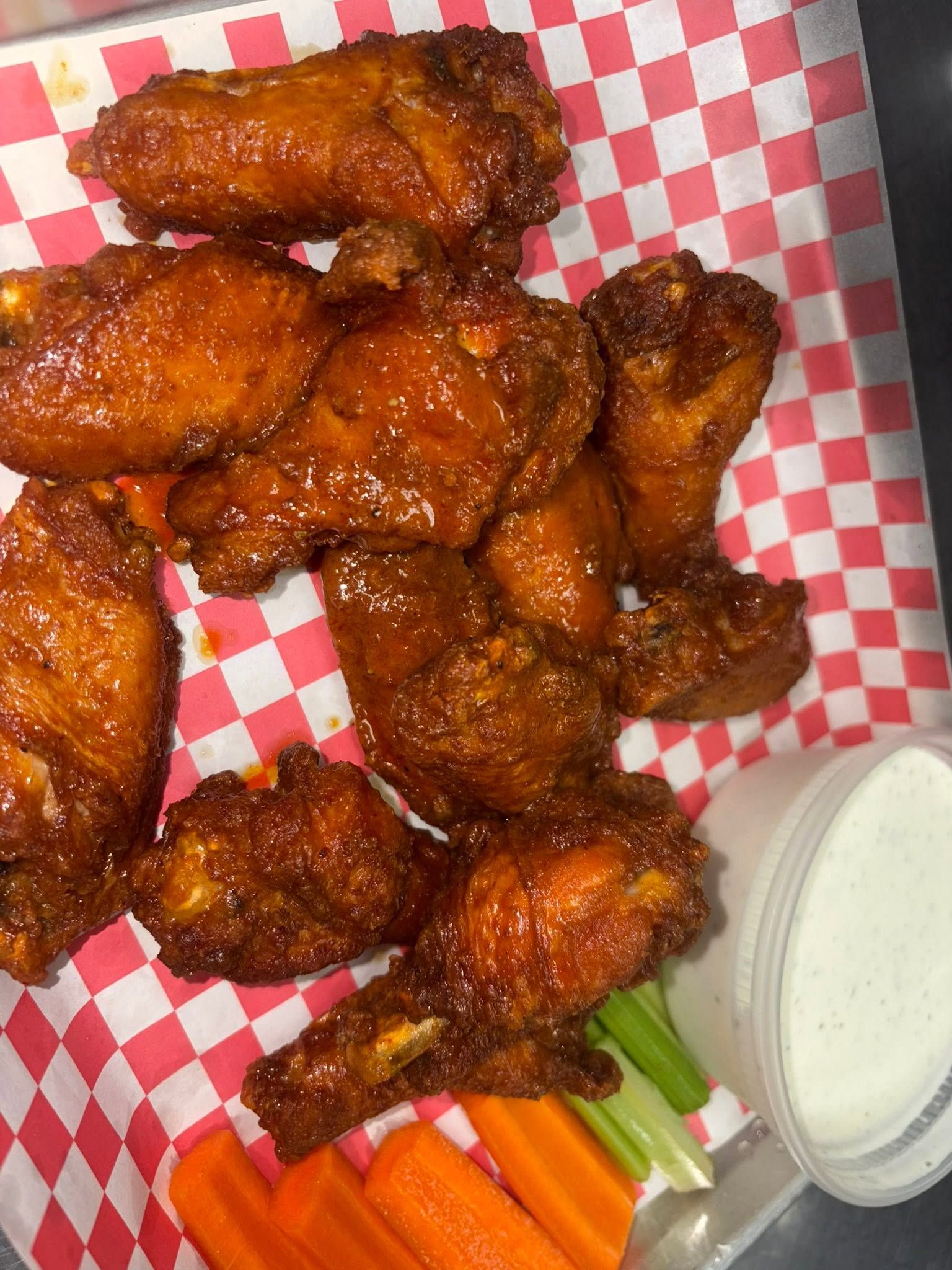 Buffalo wings in a checkered basket with carrots, celery and ranch