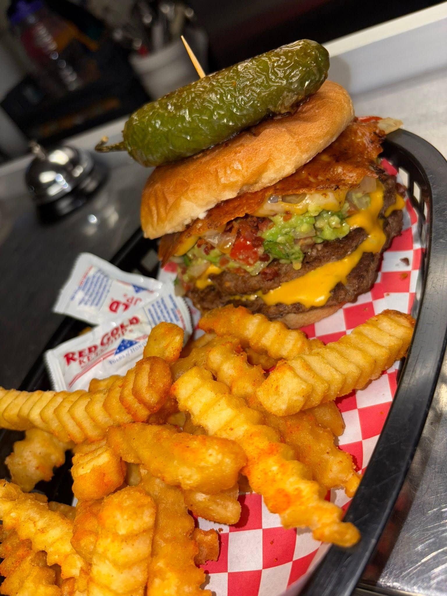 A bacon guacamole burger with a pickled jalapeño and crinkle-cut fries