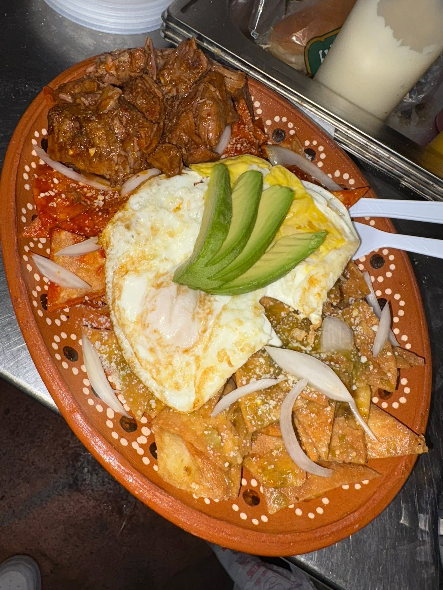 Chilaquiles rojos and verdes under fried eggs and avocado