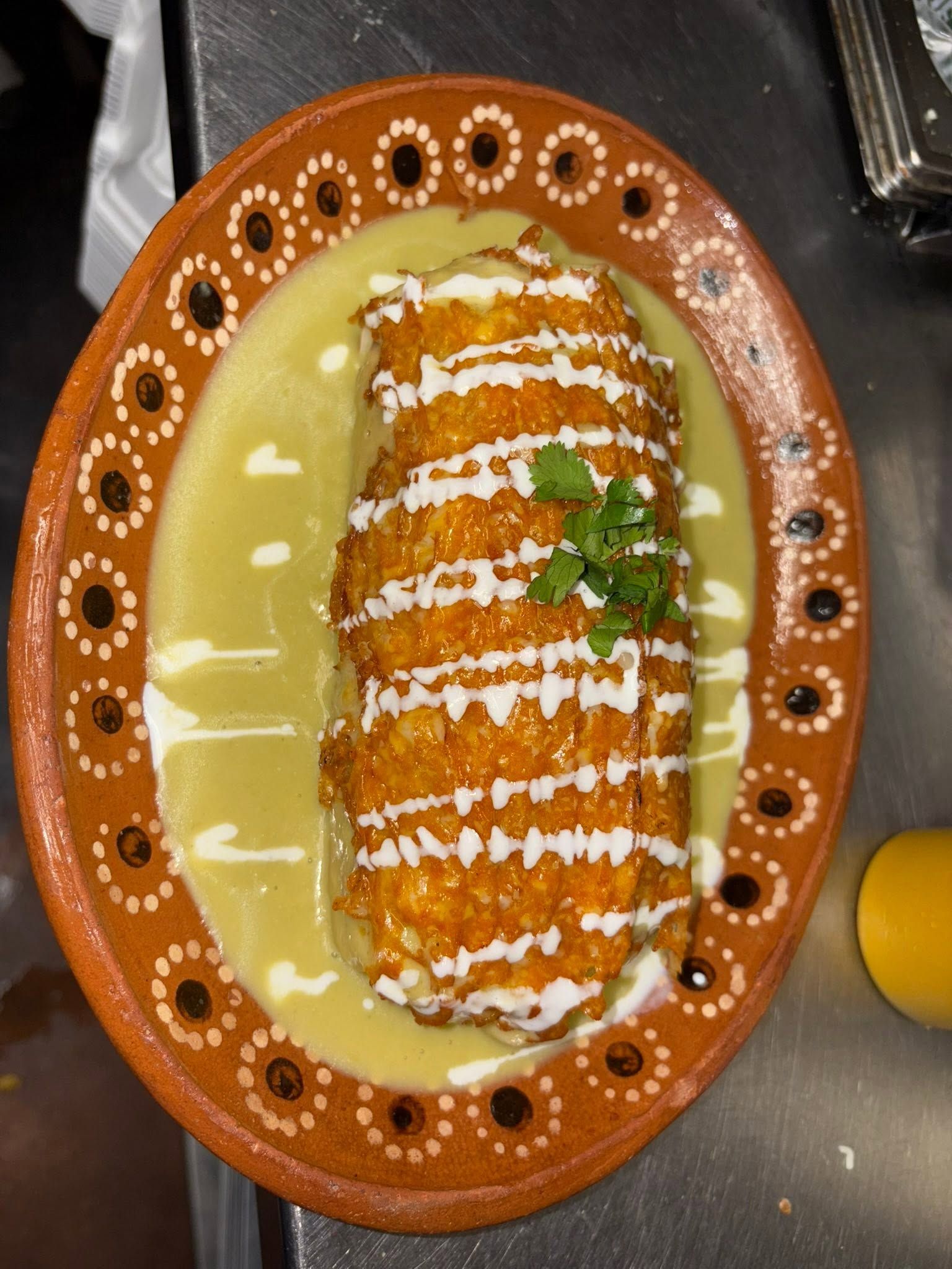 Chile relleno smothered in salsa verde and crema on a decorative clay plate