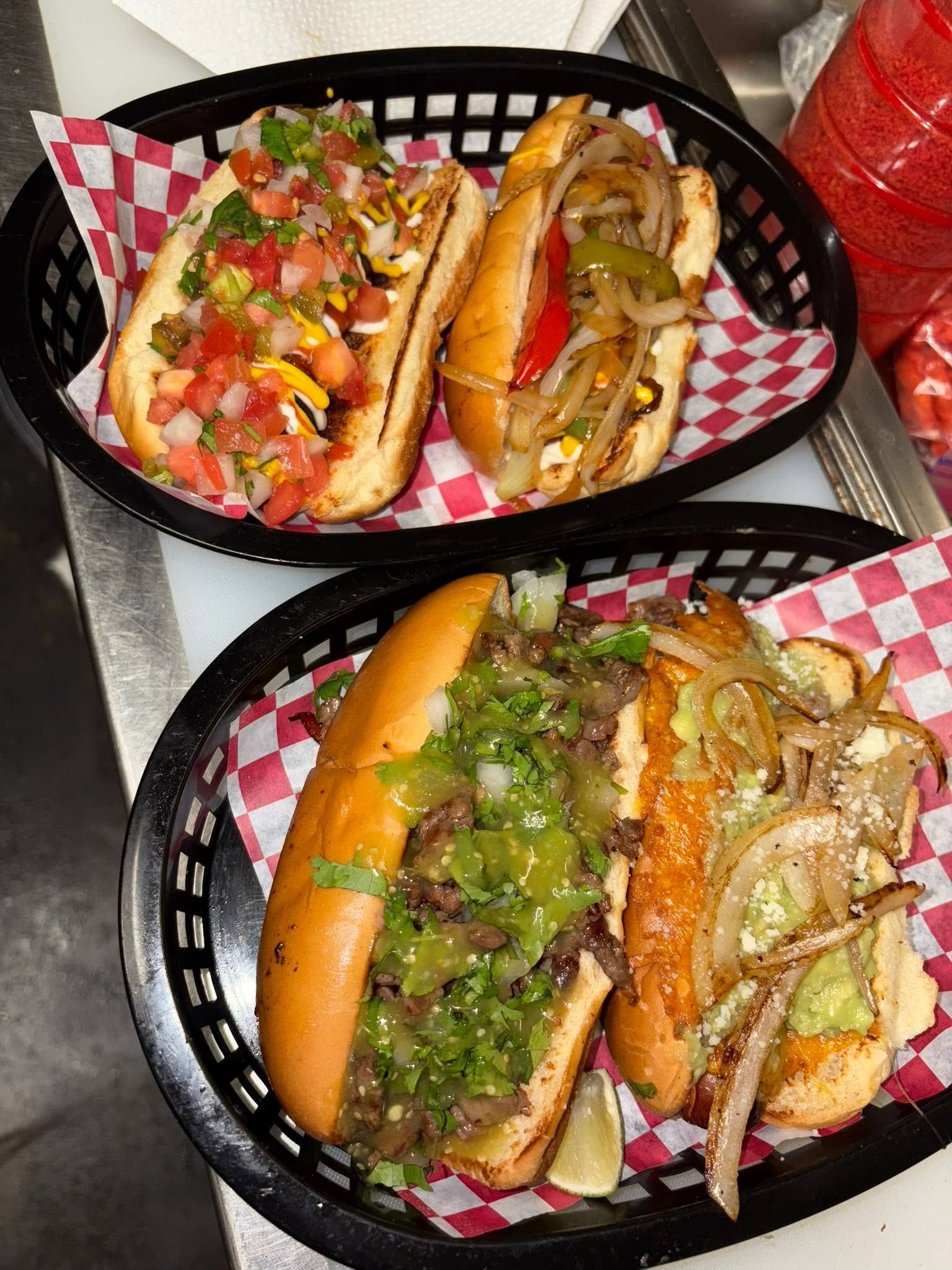 Two baskets of loaded dogos with pico de gallo, fajita veggies, steak, and cheese