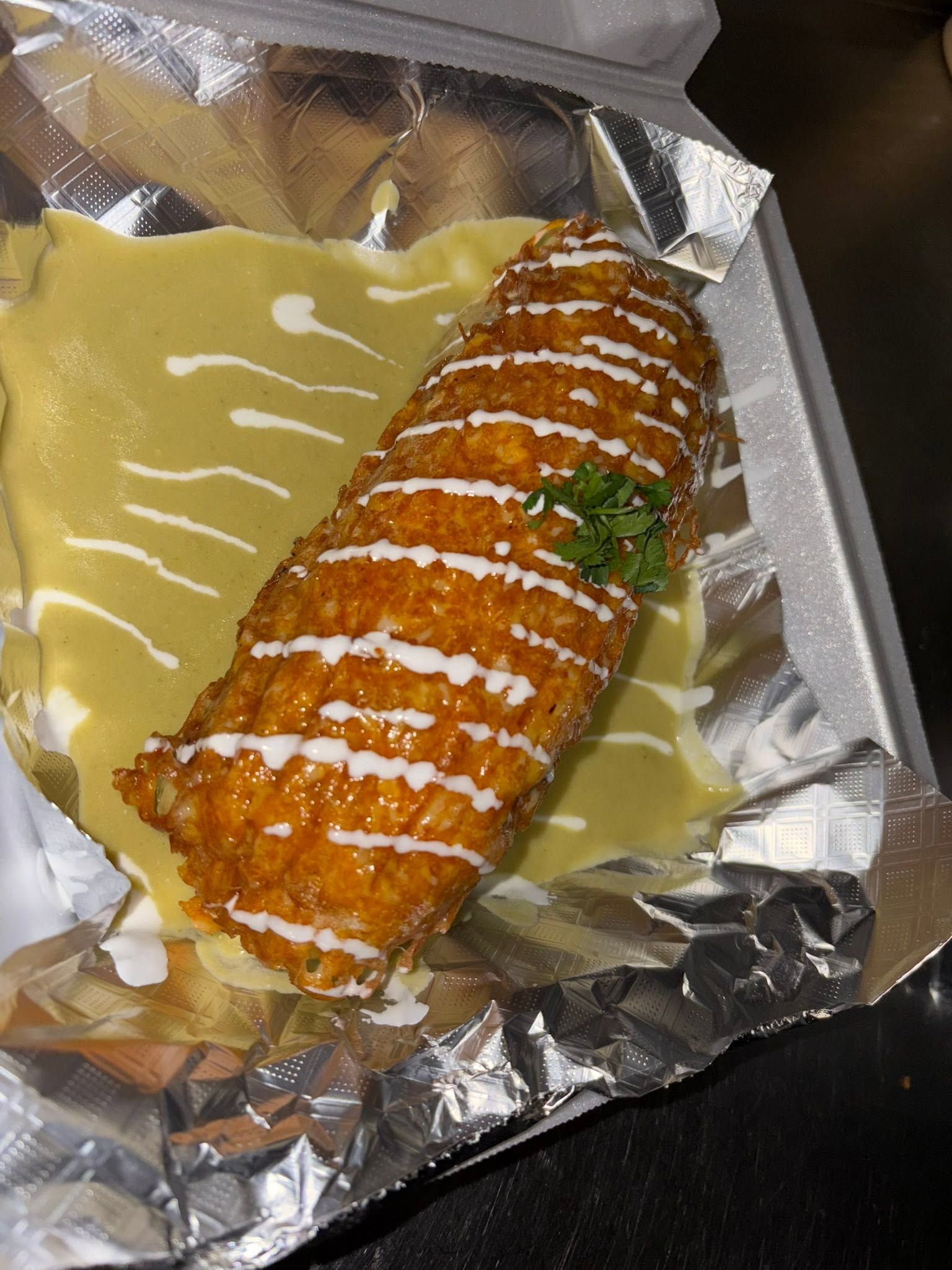 Chile relleno in green salsa with crema drizzle, packed in a to-go container