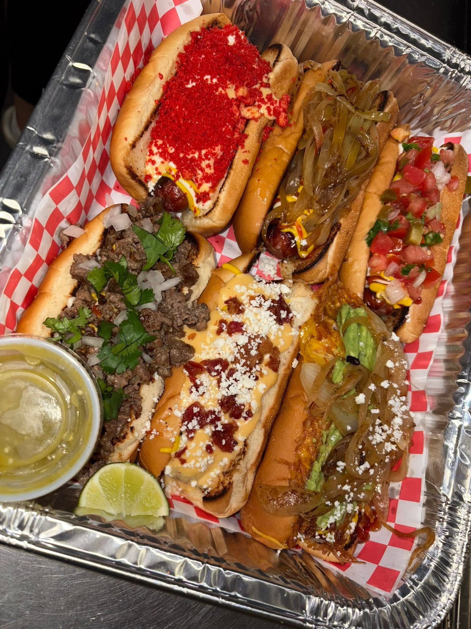 Tray of six loaded bacon-wrapped dogos with Hot Cheetos, carne asada, queso, and guacamole toppings