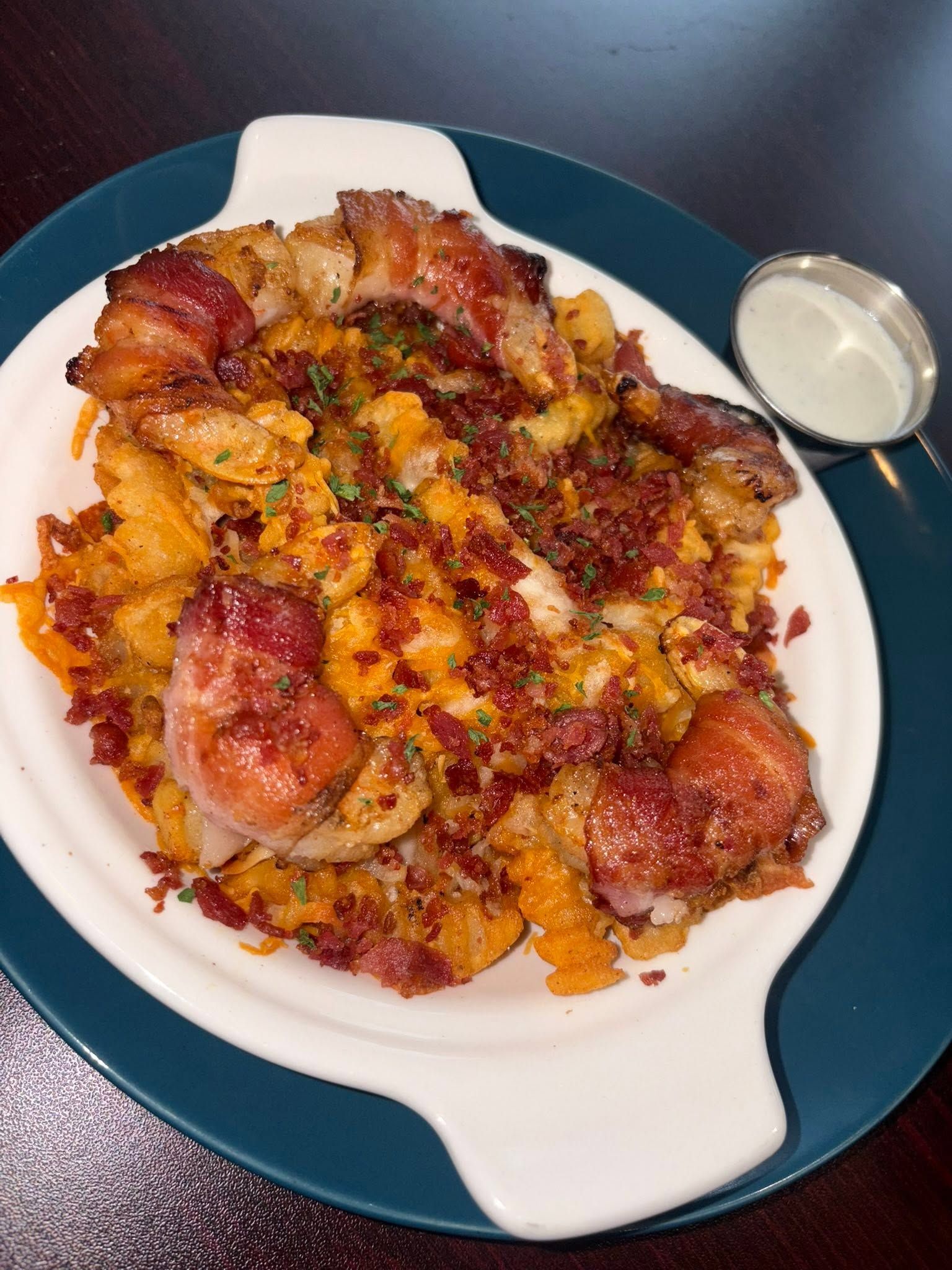 Bacon-wrapped shrimp over cheese fries with bacon bits and ranch