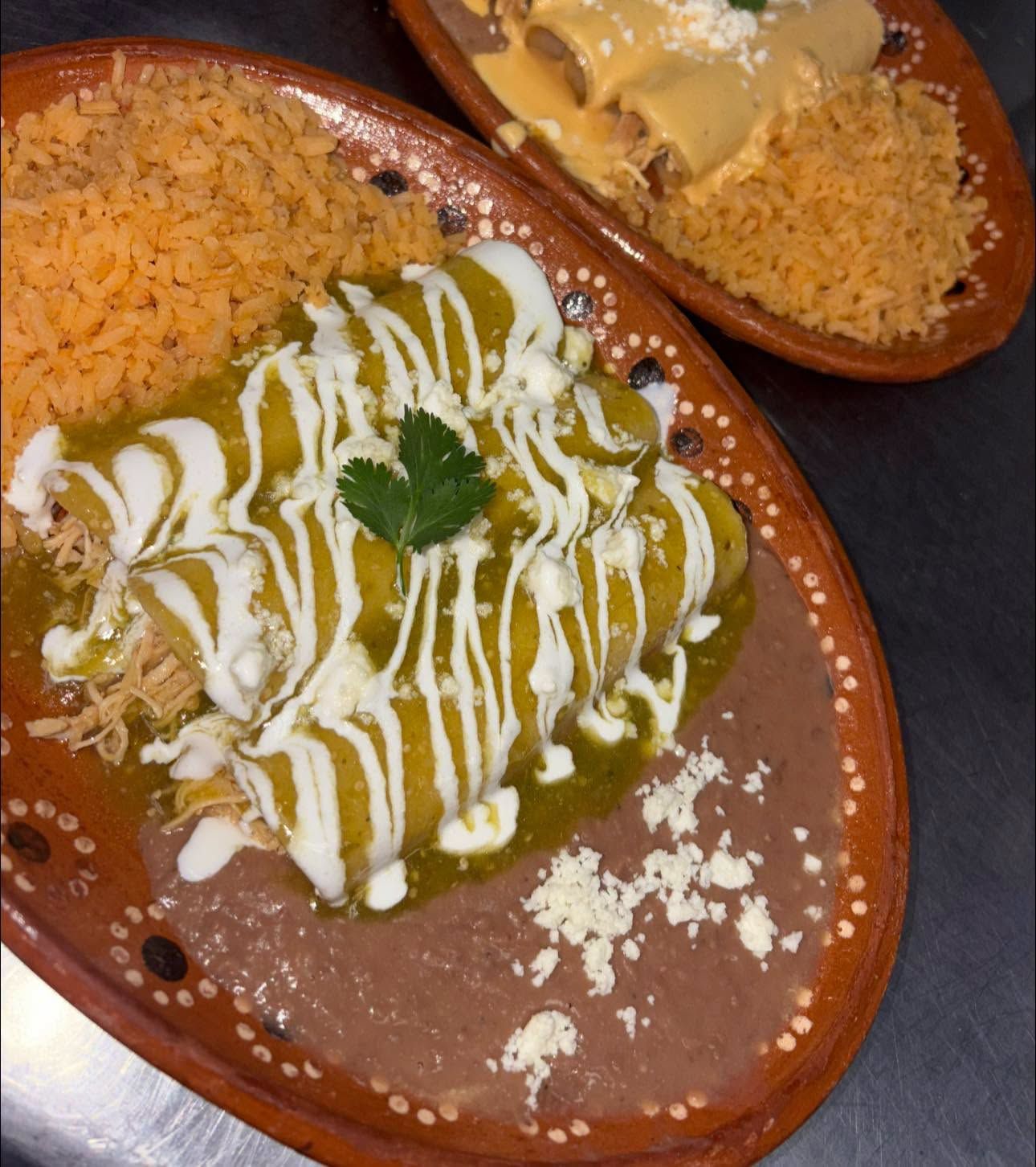 Green sauce chicken enchiladas verdes with crema and cotija, served with rice and beans