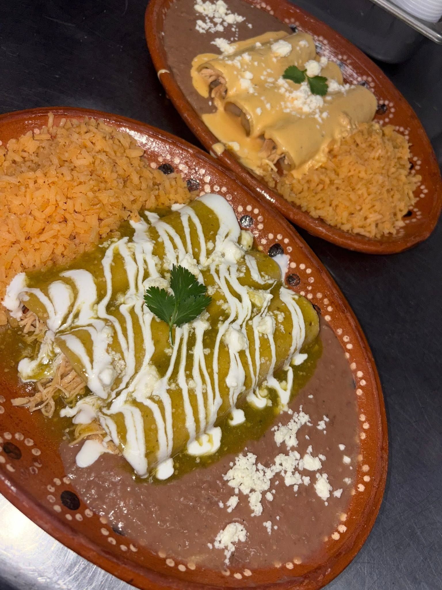 Enchiladas verdes with crema and cotija beside rice and beans