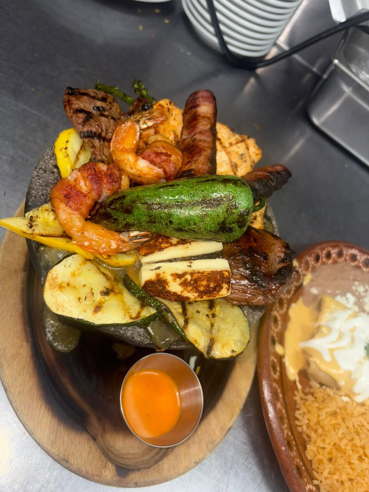 Mixed grill of bacon-wrapped shrimp, steak, sausage and a roasted jalapeño