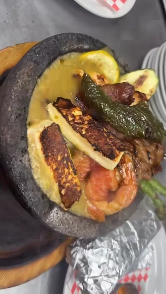 Molcajete mixed grill with shrimp, steak, grilled queso and poblano peppers in stone bowl