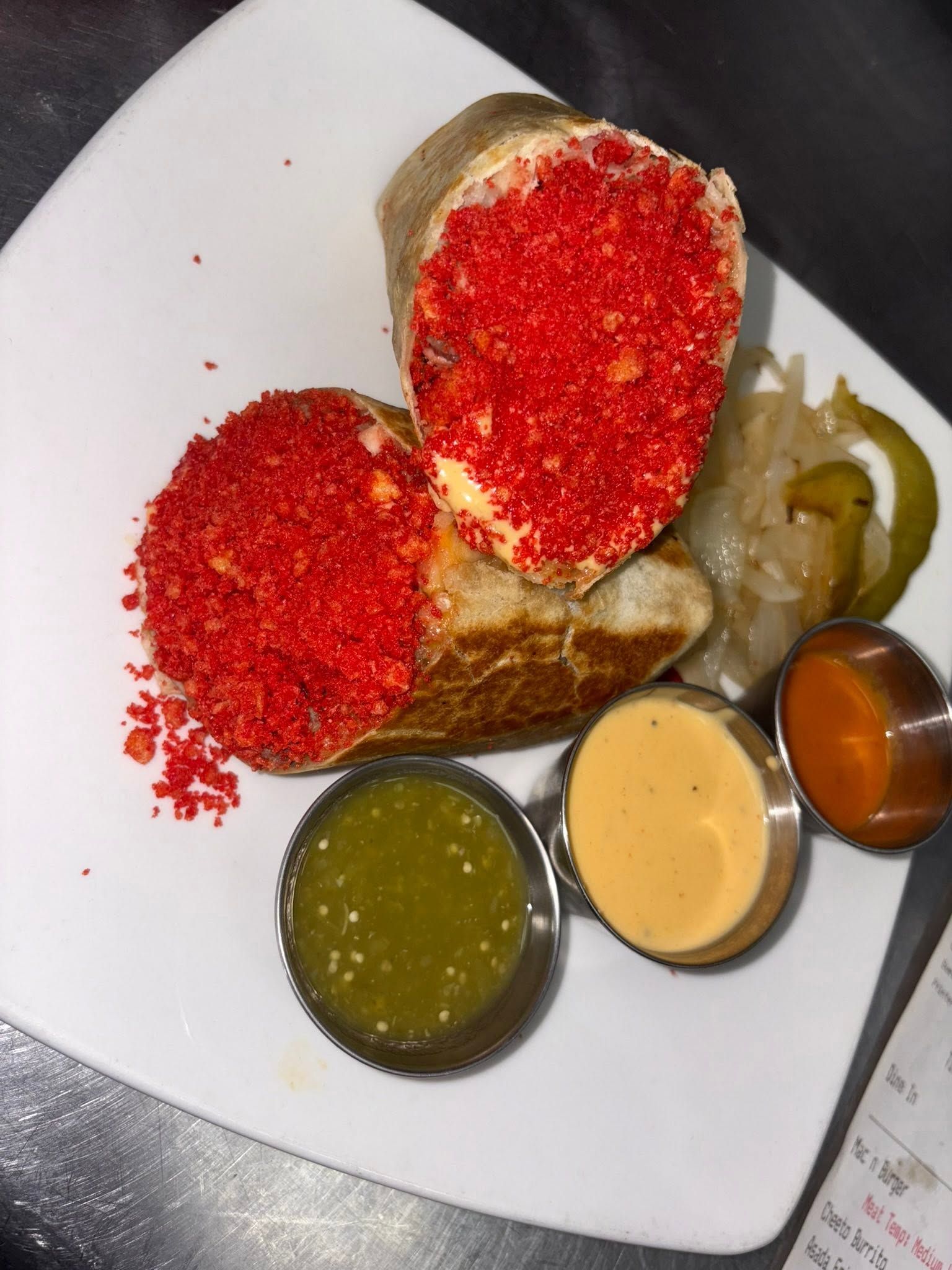 Halved red chile-crusted torta with pickled onion, jalapeño rings and three dipping salsas